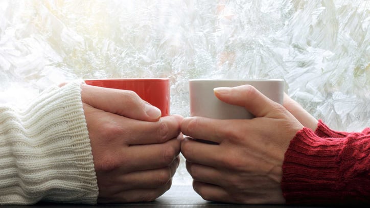 two mugs together with hands wrapped around each one