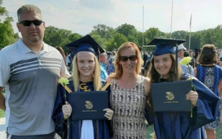 two teenage girls in graduation caps and gowns with parents