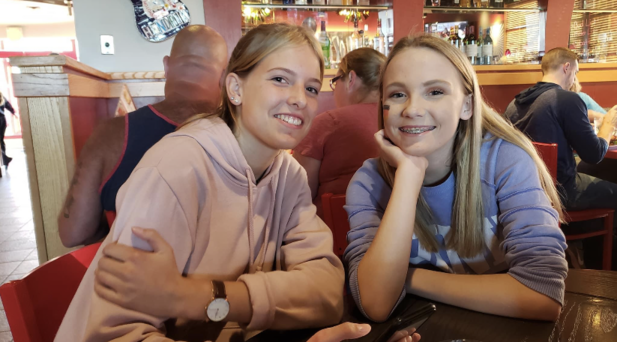 two teenage girls sitting together in cafe and smiling
