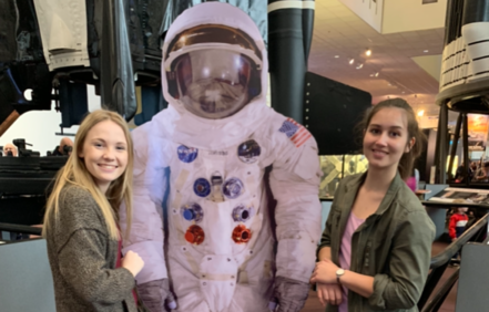 two teenage girls with astronaut mannequin at aerospace museum