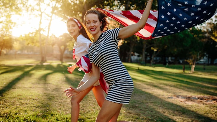 two teenager girls running with an American flag
