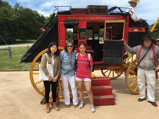 woman and two girls in front of a stagecoach