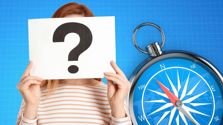 woman holding question mark sign with compass in background