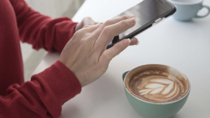 woman messaging on phone while having coffee