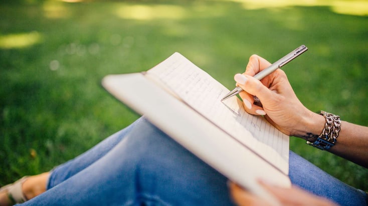 woman sitting on the grass writing in journal