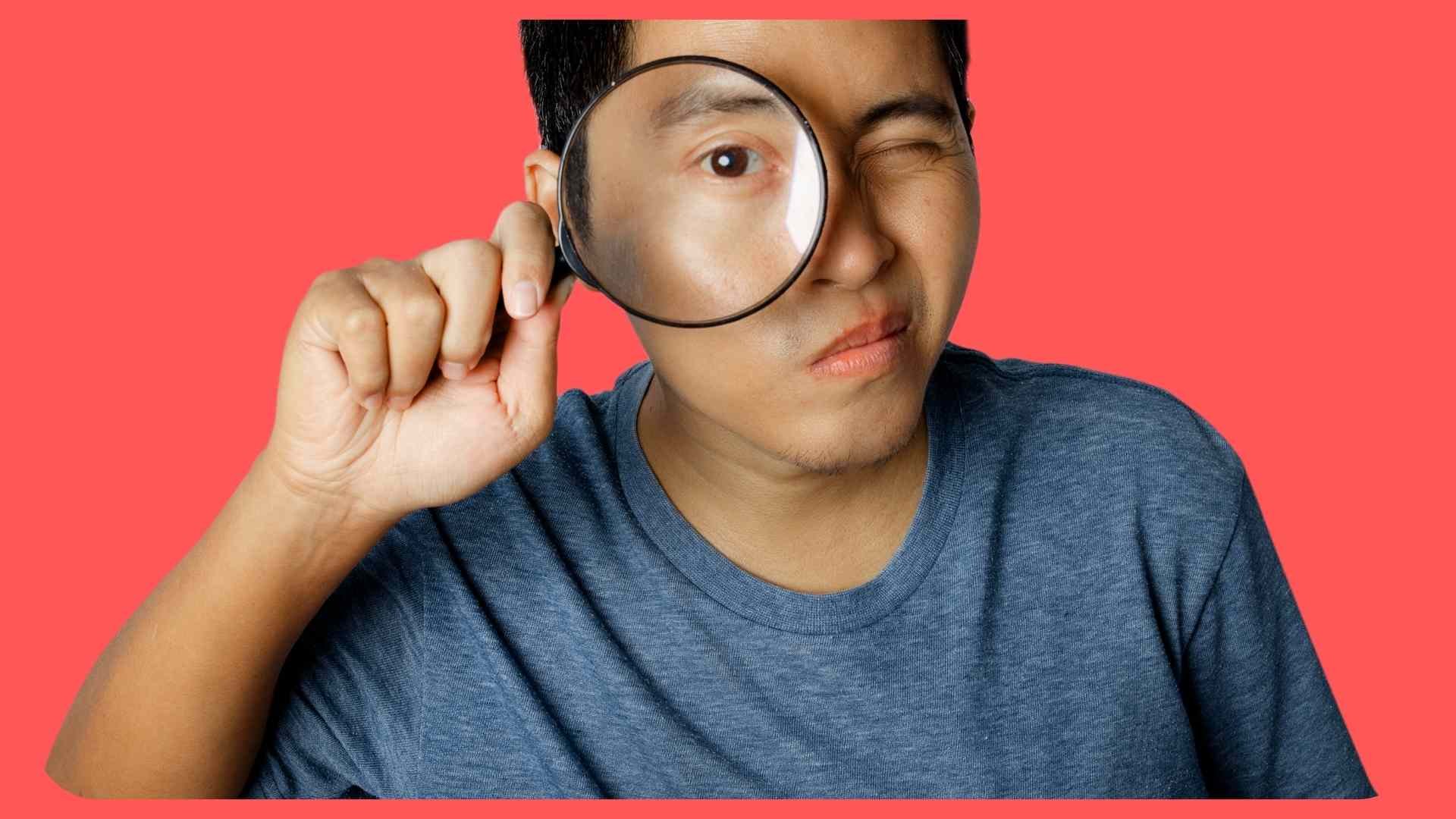 young man looking through magnifying glass