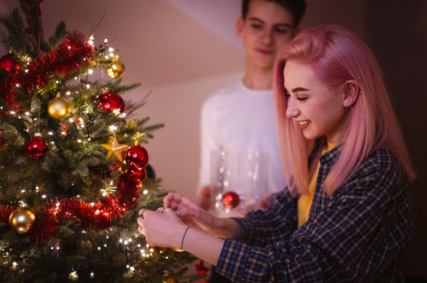 teen girl putting ornament on xmas tree