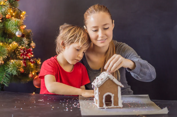 teen girl and child making gingerbread house