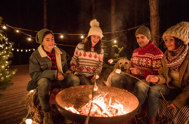 family roasting marshmallows around fire