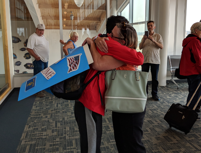 woman hugging teen at airport