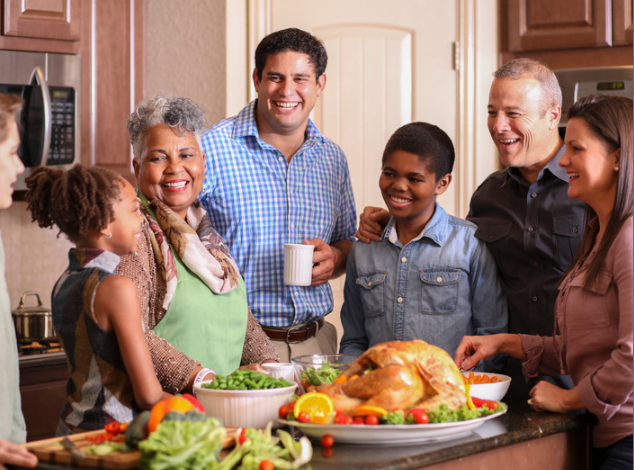 family in kitchen laughing around turkey