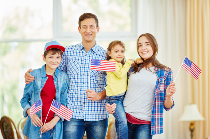 family dressed in red white and blue holding flags